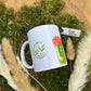 Weiße Keramiktasse mit grünem Matcha-Motiv und farbigem Matcha-Drink-Print, auf Moos liegend