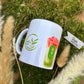 Personalisierbare 330ml Matcha Motiv-Tasse seitlich auf rustikalem Holz, umrahmt von Pampasgras und Moosdeko